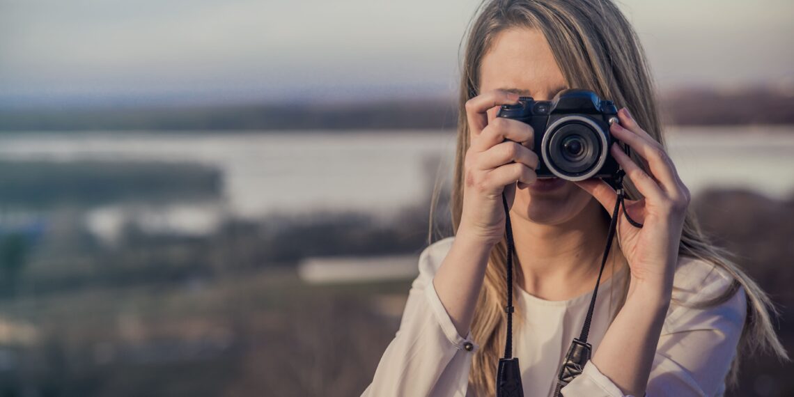 photographer-woman-girl-is-holding-dslr-camera-taking-photographs-smiling-young-woman-using-camera-take-photo-outdoors (1)